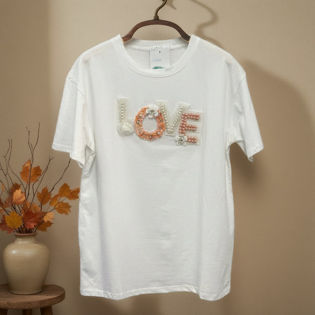 Camiseta Cuore algodón manga corta aplique LOVE perlas lentejuelas colgada en un ambiente para mujer Angara Moda