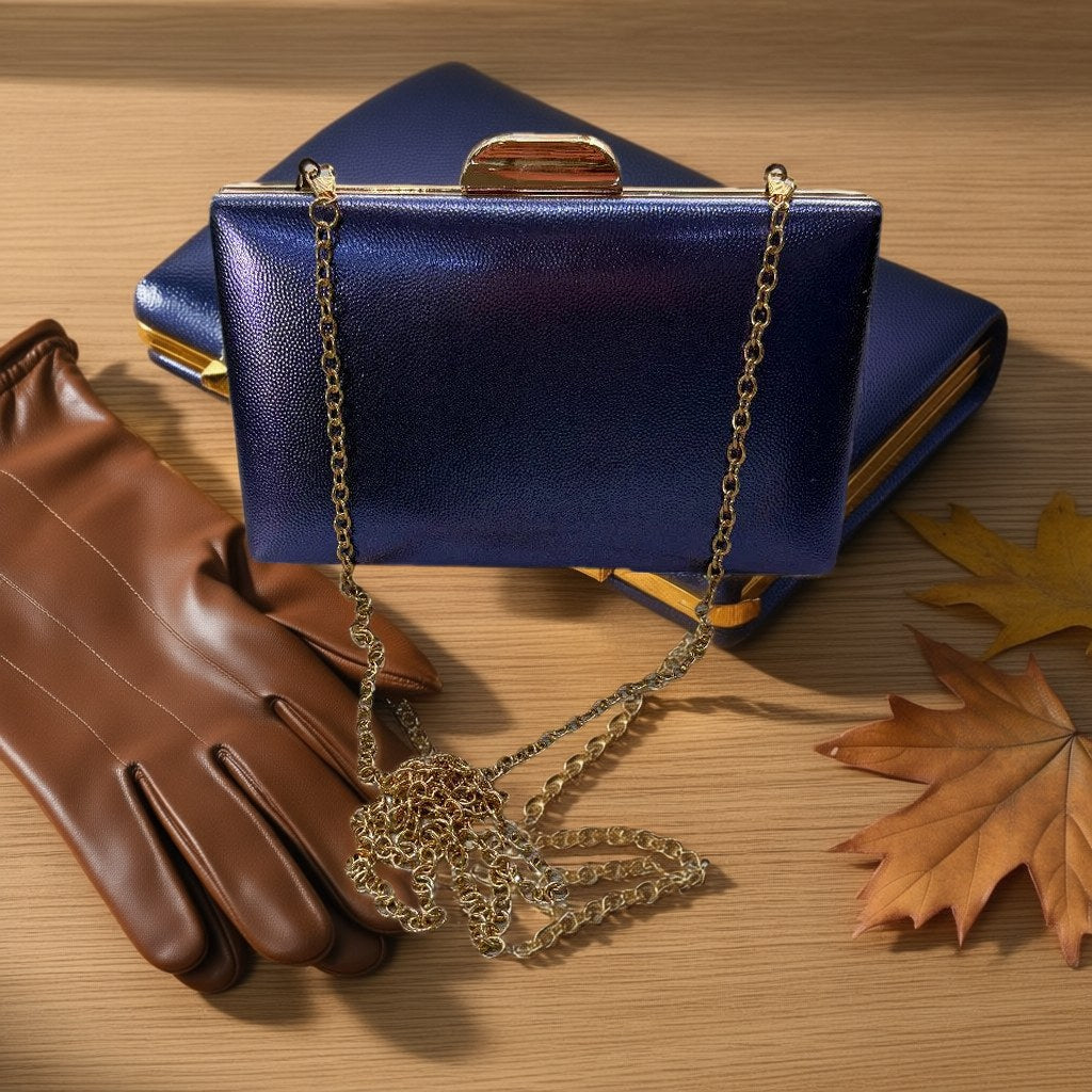 Bolso Luciano clutch de acabado pebble con cierre dorado y cadena desmontable desde arriba con gafas de sol y pulsera para mujer Angara Moda