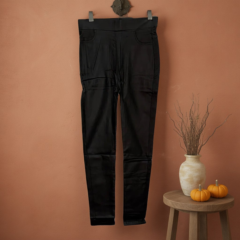 Pantalón pitillo efecto cuero con cintura alta elástica Prieto colgada en un ambiente para mujer Angara Moda