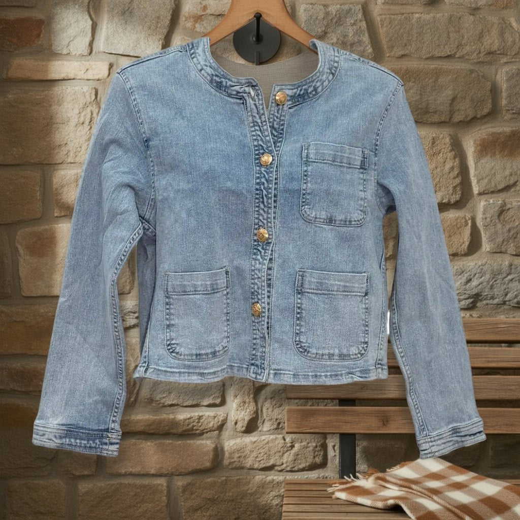 Chaqueta Vaquera Ember con Botones Dorados y Bolsillos Parche colgada en un ambiente para mujer Angara Moda