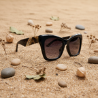 Gafas de sol oversize cat eye flat lay fondo arena natural Angara Moda