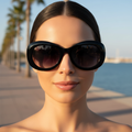 Gafas de sol ovaladas acetato negro sobre modelo paseo marítimo Angara Moda