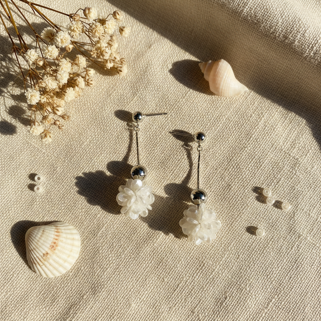 Flat lay pendientes bola floral iridiscente con complementos naturales Angara Moda