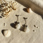 Flat lay pendientes bola floral iridiscente con complementos naturales Angara Moda